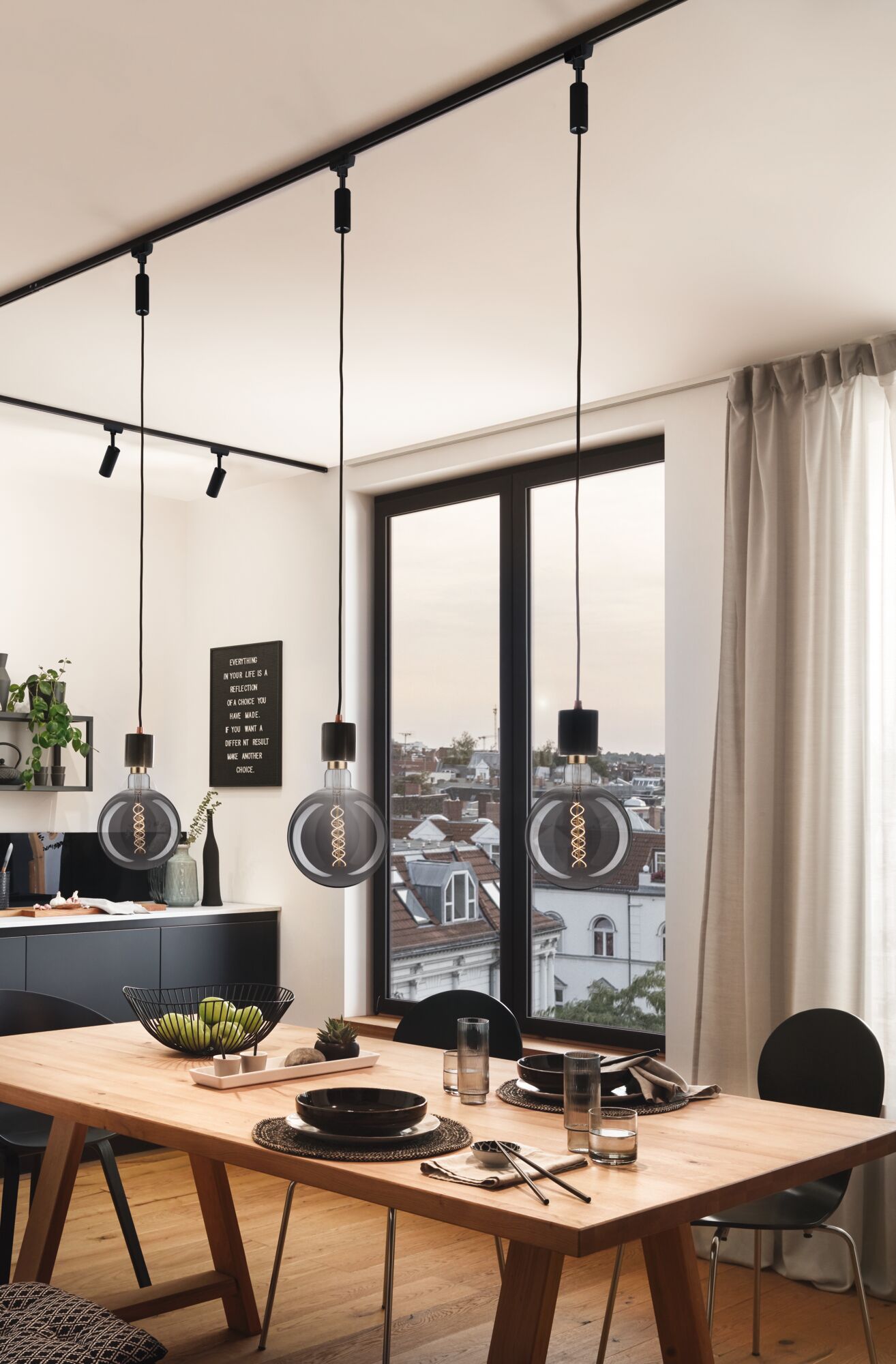 Drei schwarze Pendelleuchten mit Glühfaden-LED über hellem Holztisch im modernen Esszimmer mit Stadtblick