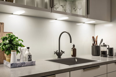 Moderne køkkenbordplade med sort vask, mat sort vandhane og LED-underkabinetbelysning.