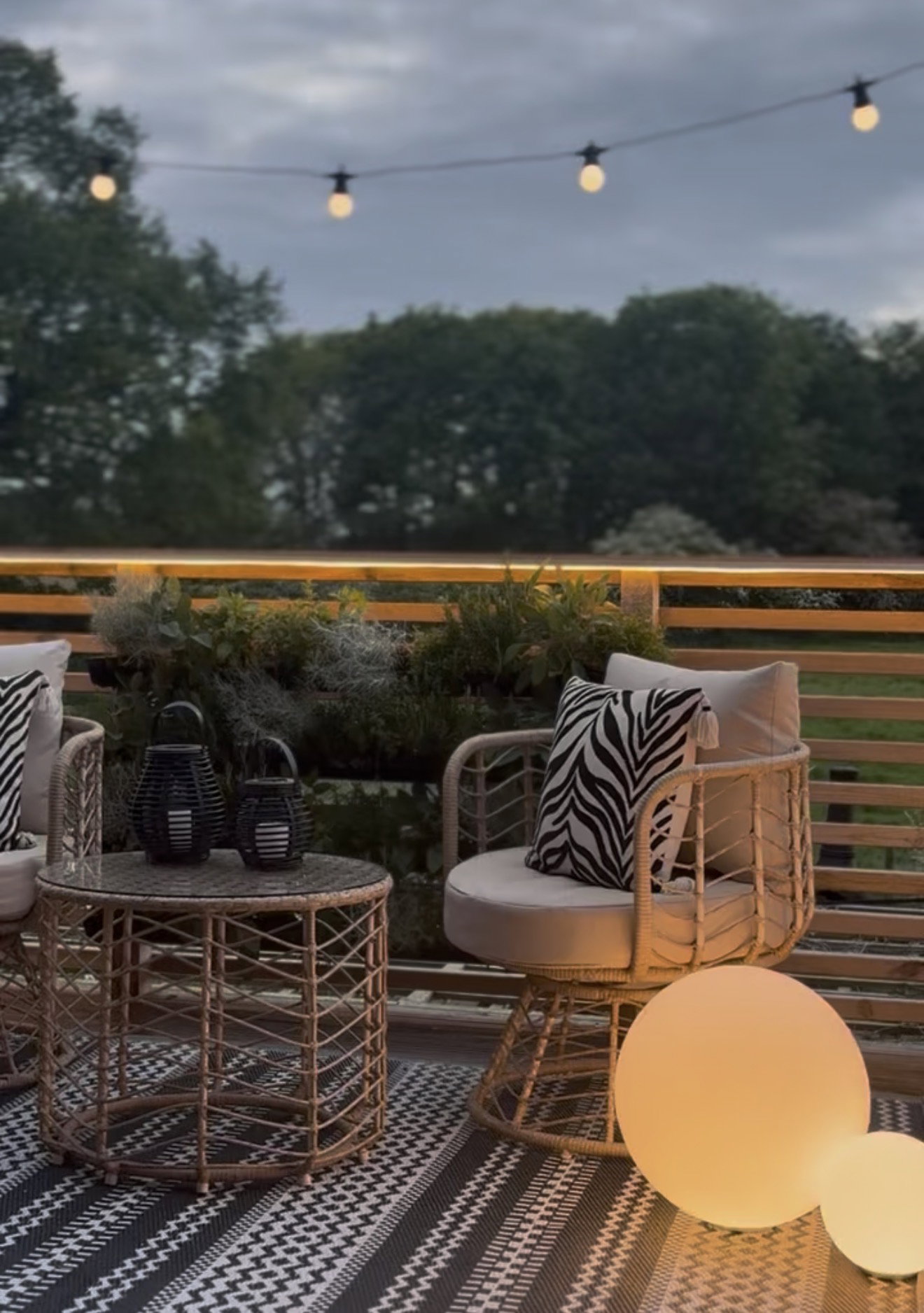 Cozy balcony rattan furniture set with zebra cushion and warm glowing LED spheres for outdoor lighting