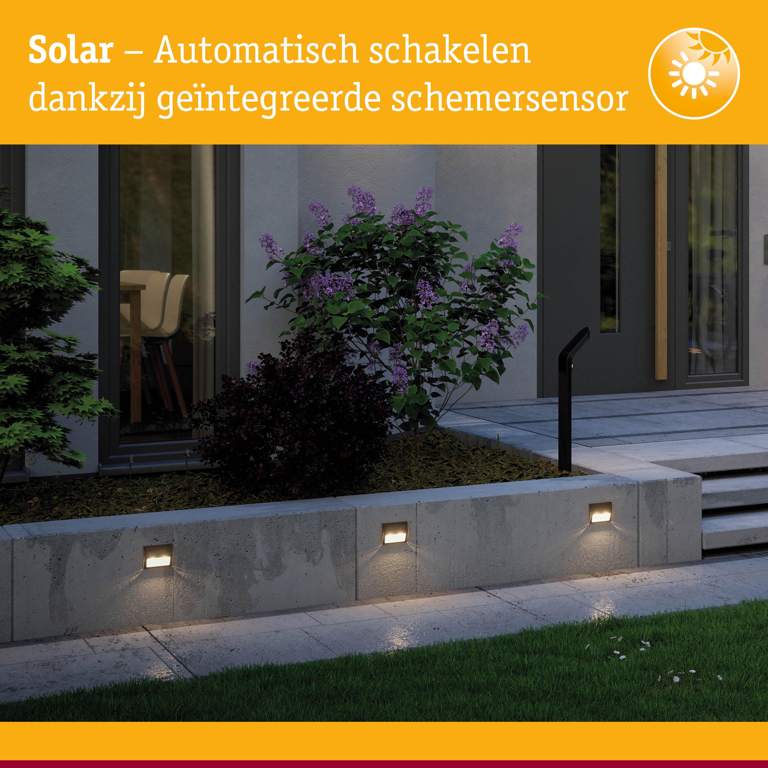 Zonne-energie buitenmuurlampen met geïntegreerde schemersensor op grijze betonnen muur verlichten tuinpad