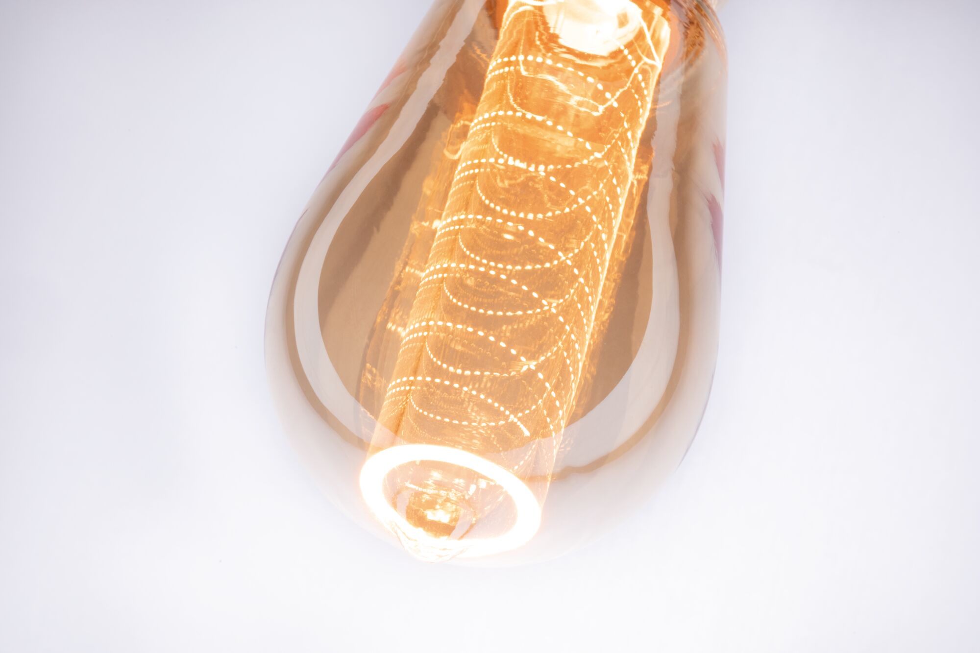Close-up of warm white LED bulb with decorative filament and amber-colored glass for ambient lighting