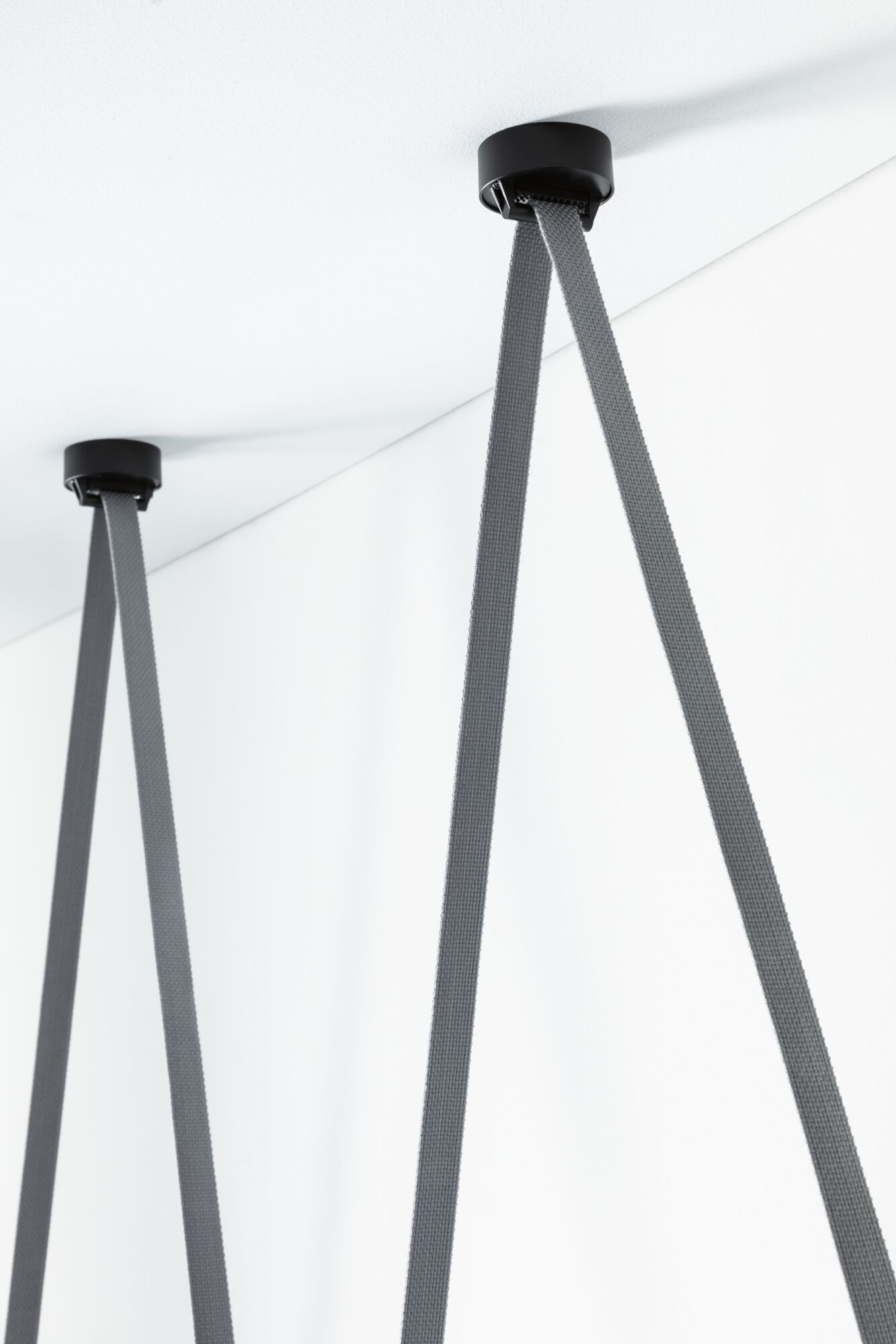 Supports de plafond noirs avec sangles textiles grises pour suspensions LED modernes en intérieur.