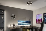 Modern office with black circular LED ceiling light emitting warm white light above gaming desk setup