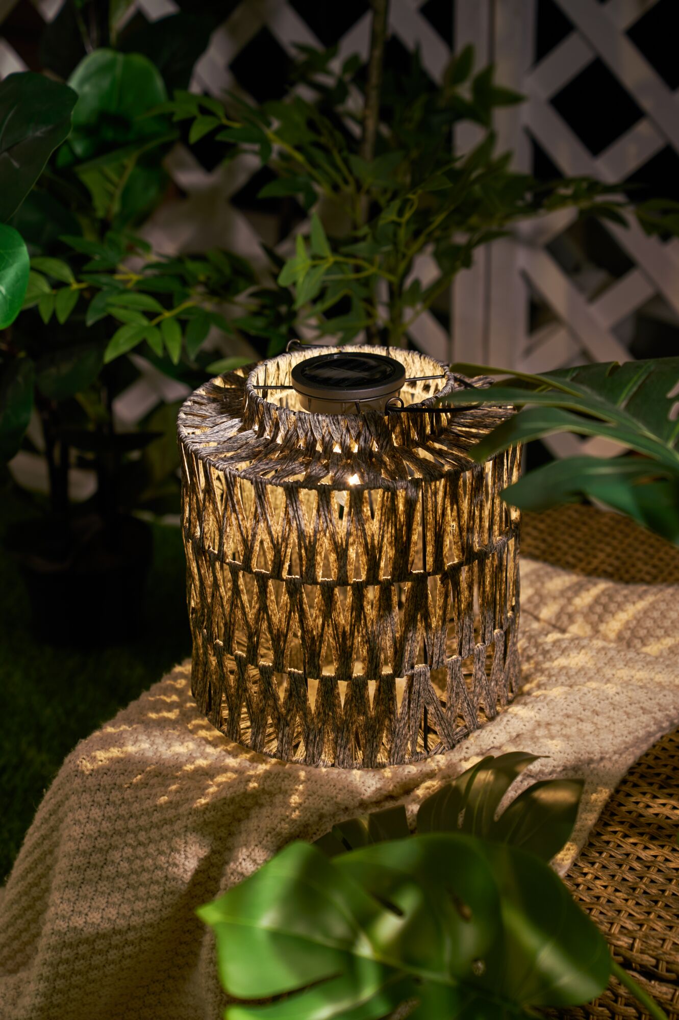 Solar-powered outdoor lantern made of woven natural material in brown for garden and patio lighting
