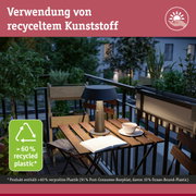 Moderne Tischlampe aus recyceltem Kunststoff auf Balkon mit Holztisch und Pflanzen bei Abendlicht
