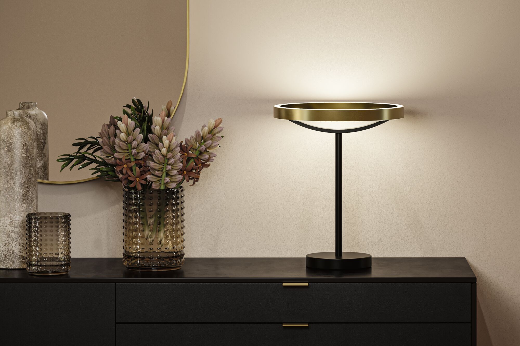 Modern table lamp with gold metal ring and black stand on black sideboard with decorative vase.
