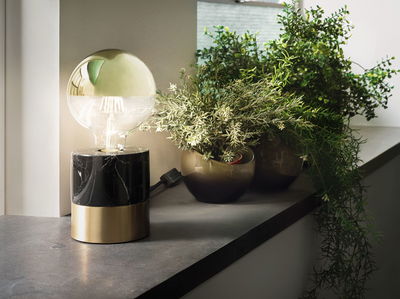 Moderne Tischlampe mit schwarzem Marmor- und Messingfuß neben grünen Pflanzen auf Fensterbank