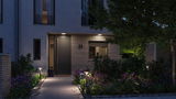Modern outdoor lighting with warm white LED bollard lights and ceiling lights at entrance with garden path.