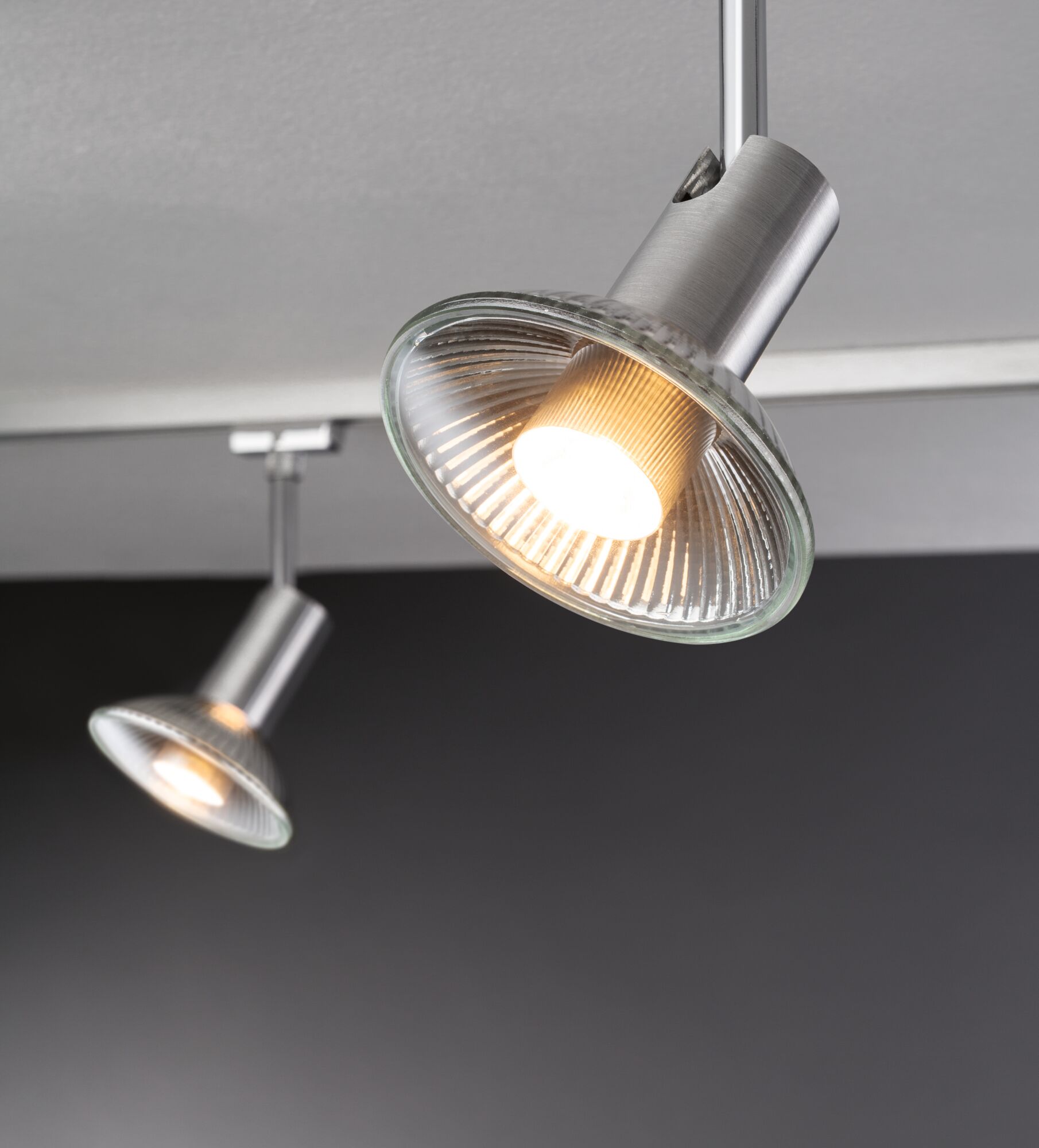 Zwei moderne Deckenstrahler aus gebürstetem Aluminium mit klarem Glasreflektor und warmweißem Licht