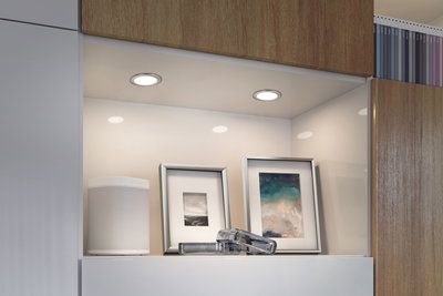 Hvide LED-indbygningslamper i moderne køkkenniche med billedrammer og højttaler.