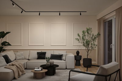 Moderne woonkamer met beige hoekbank, zwarte accenten en minimalistische plafondverlichting