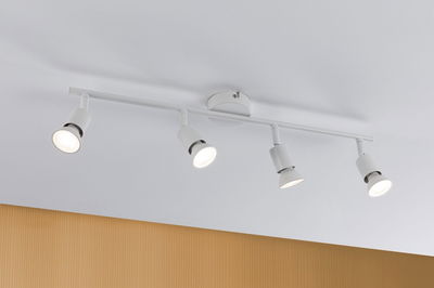 Modern white ceiling spotlight with four adjustable metal lamps for living room lighting.