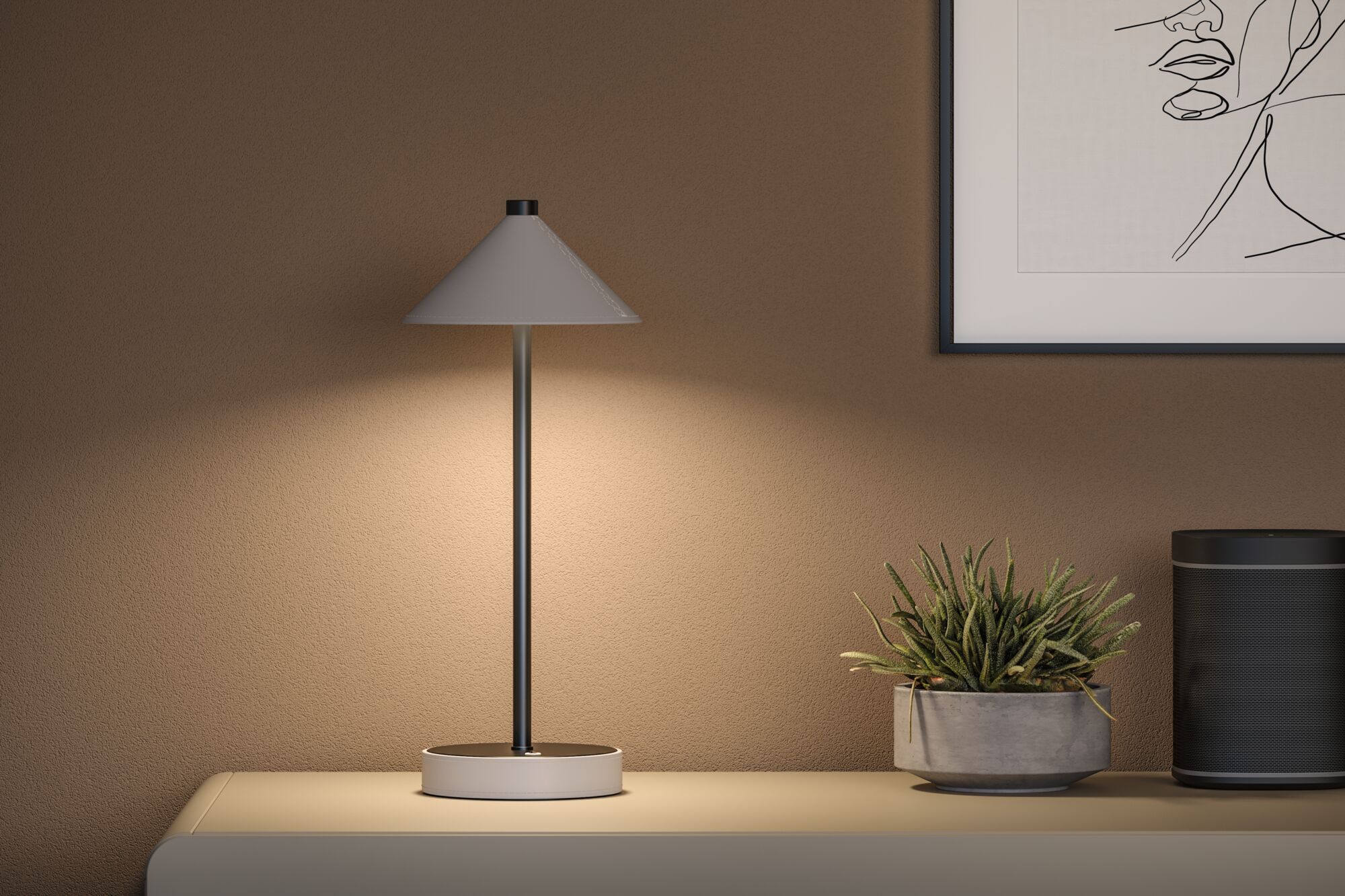 Moderne Tischlampe mit grauem Metallfuß und konischem Schirm auf Sideboard neben Pflanze und Lautsprecher
