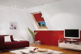 Moderne woonkamer met rode bank, wit vloerkleed, witte kabelhanglampen en houten vloer