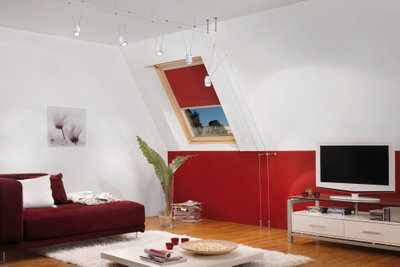 Moderne woonkamer met rode bank, wit vloerkleed, witte kabelhanglampen en houten vloer