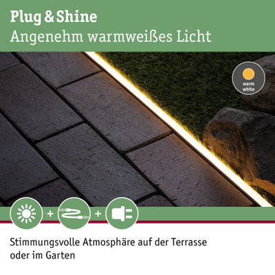 Warmweißes LED-Lichtband zwischen Pflastersteinen und Rasen für stimmungsvolle Gartenbeleuchtung