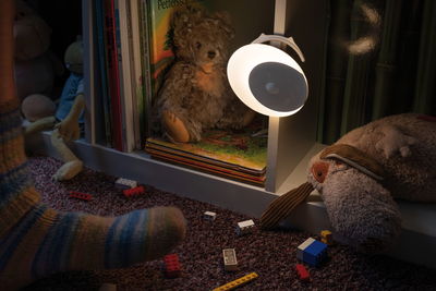 White LED night light with motion sensor on white shelf near stuffed animals and children's books.