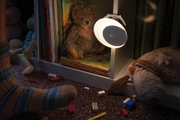 Weiße LED-Nachtlampe mit Bewegungsmelder an weißem Regal neben Kuscheltieren und Kinderbüchern.