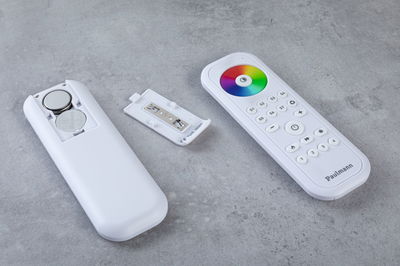 White remote control with color wheel and open battery compartment on gray surface, LED light control