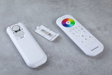 White remote control with color wheel and open battery compartment on gray surface, LED light control