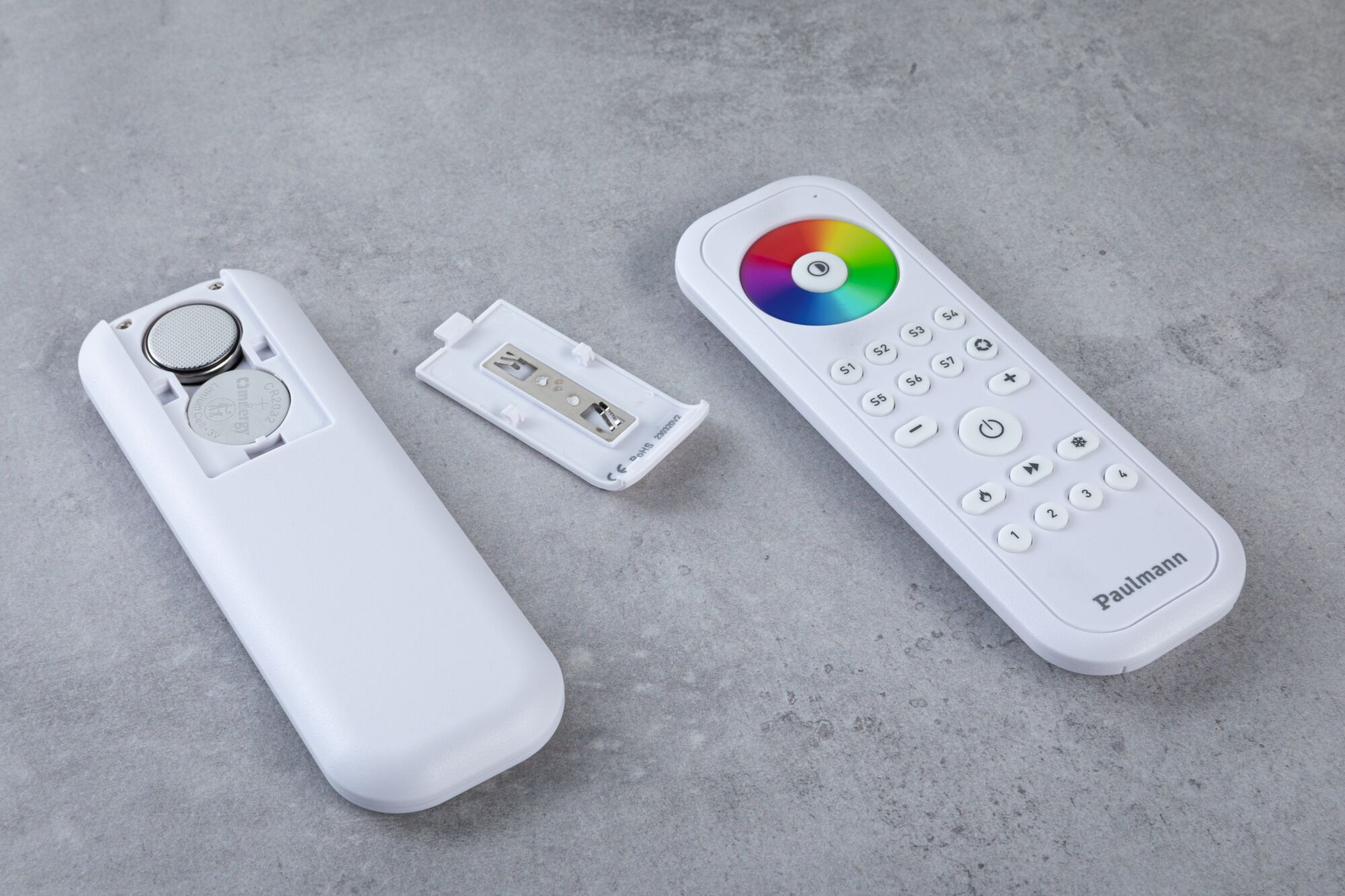 White remote control with color wheel and open battery compartment on gray surface, LED light control