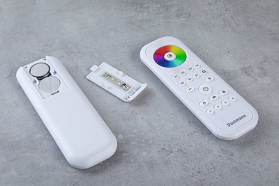 White remote control with color wheel and open battery compartment on gray surface, LED light control