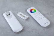 Weiße Fernbedienung mit Farbkreis und Batteriefach offen auf grauem Untergrund, LED Lichtsteuerung