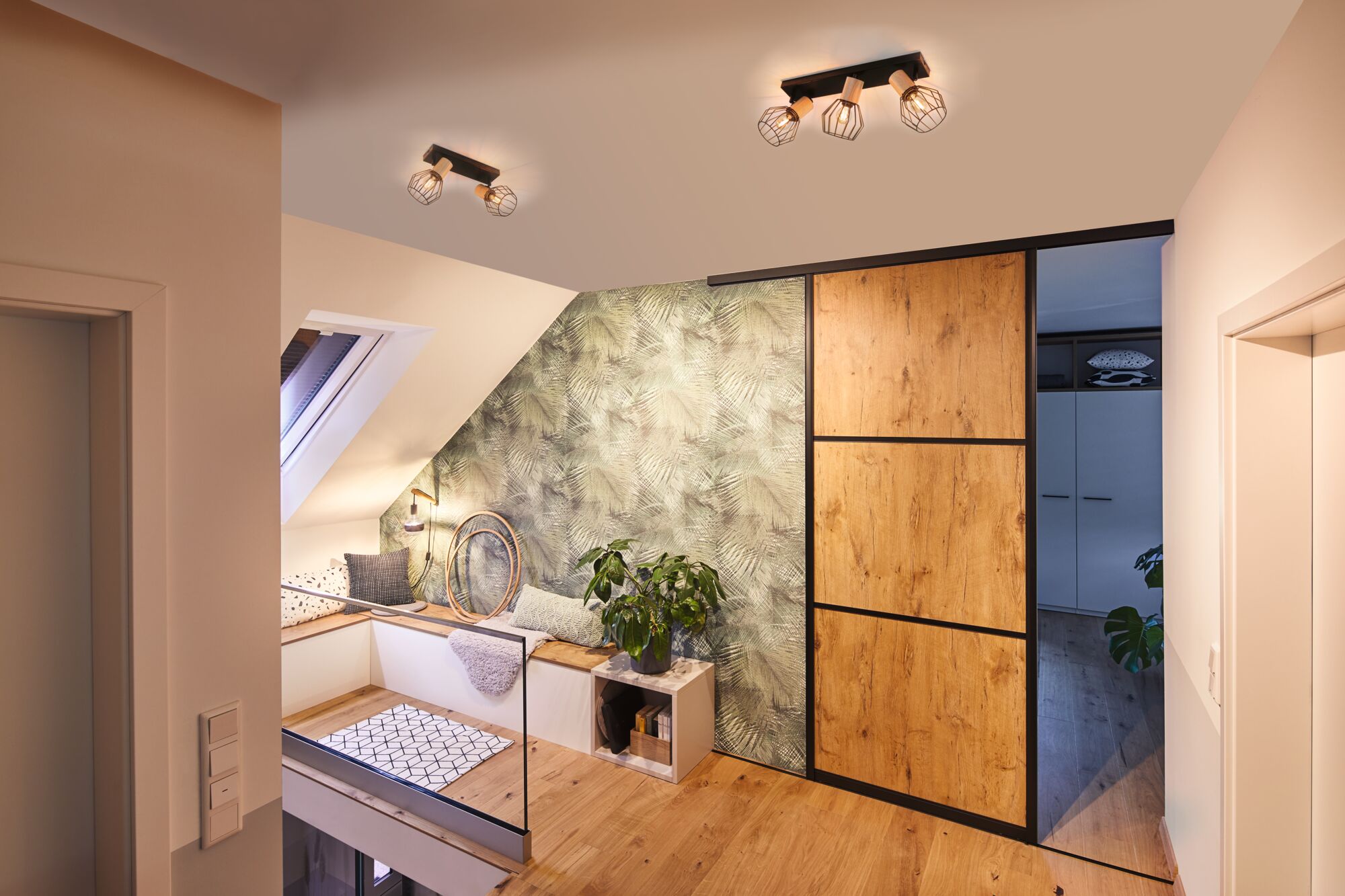 Modern living space with wooden sliding door, green patterned wall, and black copper metal cage ceiling lights.