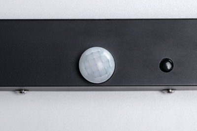 Nahaufnahme eines schwarzen Sensors mit weißer, facettierter Linse auf grauem Hintergrund für Lichtsteuerung