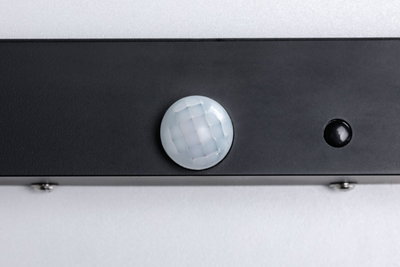 Close-up of black sensor with white faceted lens on gray background for light control technology