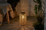 Warm light from round solar lantern made of woven natural material in living space with plants