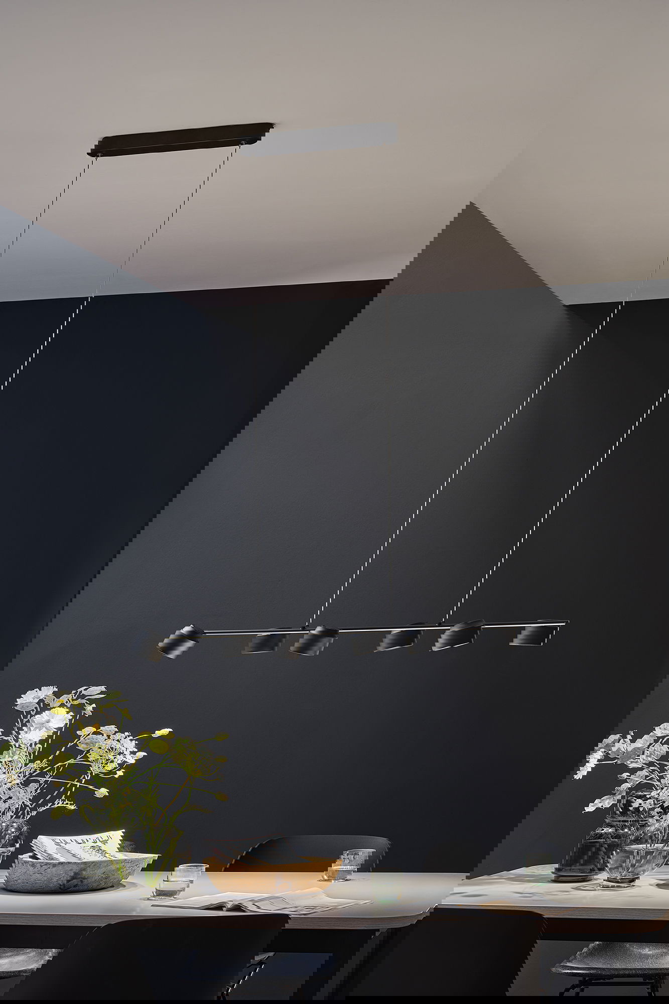 Plafonnier LED noir avec six spots réglables au-dessus d'une table à manger moderne décorée