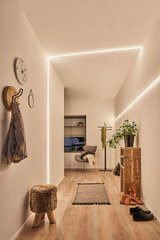 Moderne gang met MaxLED Flow warmwitte LED-strips, houten vloer en minimalistisch interieur