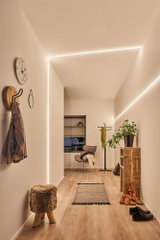 Couloir moderne avec bandes LED MaxLED Flow blanc chaud, sol en bois et décoration minimaliste