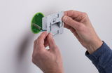 Installation of silver LED wall recessed light with green plastic housing on white wall