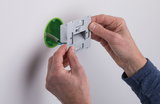 Installation d'un éclairage mural encastré LED argenté avec boîtier en plastique vert sur mur blanc