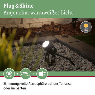 Schwarze Plug & Shine LED-Außenleuchte mit warmweißem Licht auf Kies im Garten für stimmungsvolle Terrasse