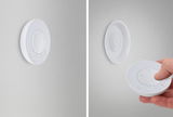 White round plastic LED dimmer on wall and handheld remote for light control