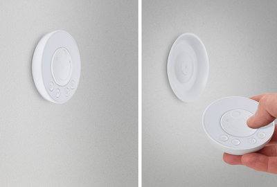 Hvid rund LED-dæmper i plastik på væg og som fjernbetjening til lysstyring