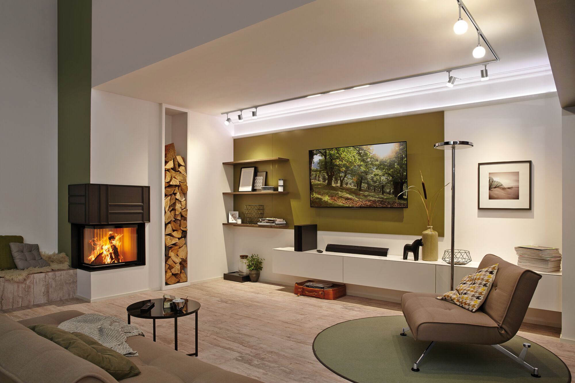 Modernes Wohnzimmer mit Kamin, braunem Sessel, grünem Teppich und LED-Deckenstrahlern für gemütliche Beleuchtung