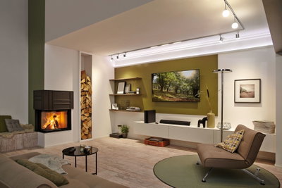 Salon moderne avec cheminée, fauteuil marron, tapis vert et spots LED au plafond pour une ambiance chaleureuse