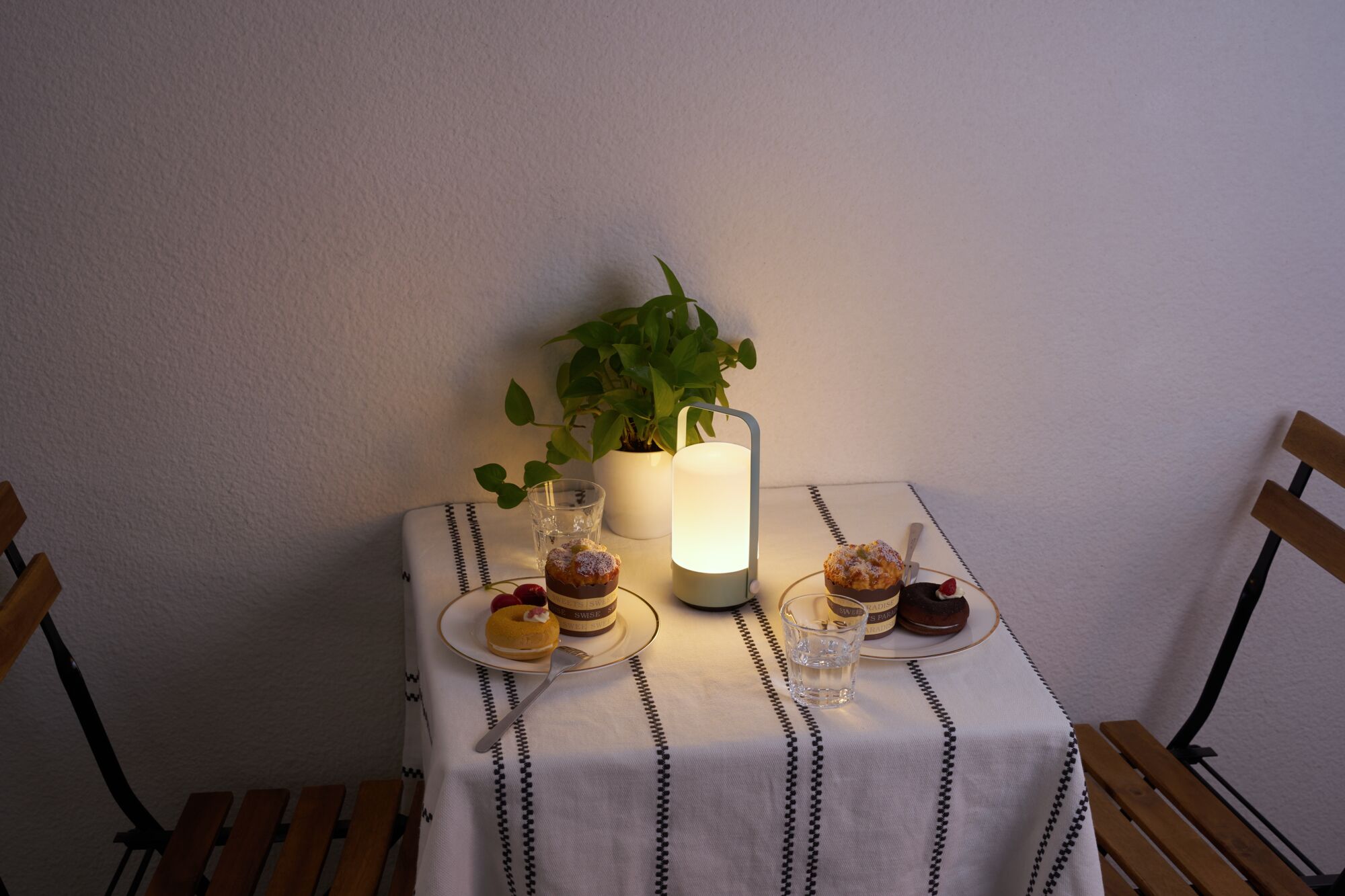 White LED table lamp with handle on table set with cakes and plant in cozy living room
