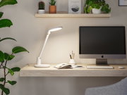 Witte LED-bureaulamp van kunststof op licht houten bureau met monitor en groene planten