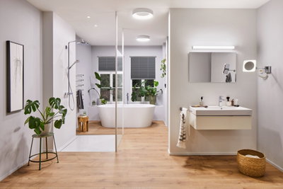 Modernes Badezimmer mit weißer Badewanne, Glasdusche, Holzfußboden und LED-Deckenleuchten
