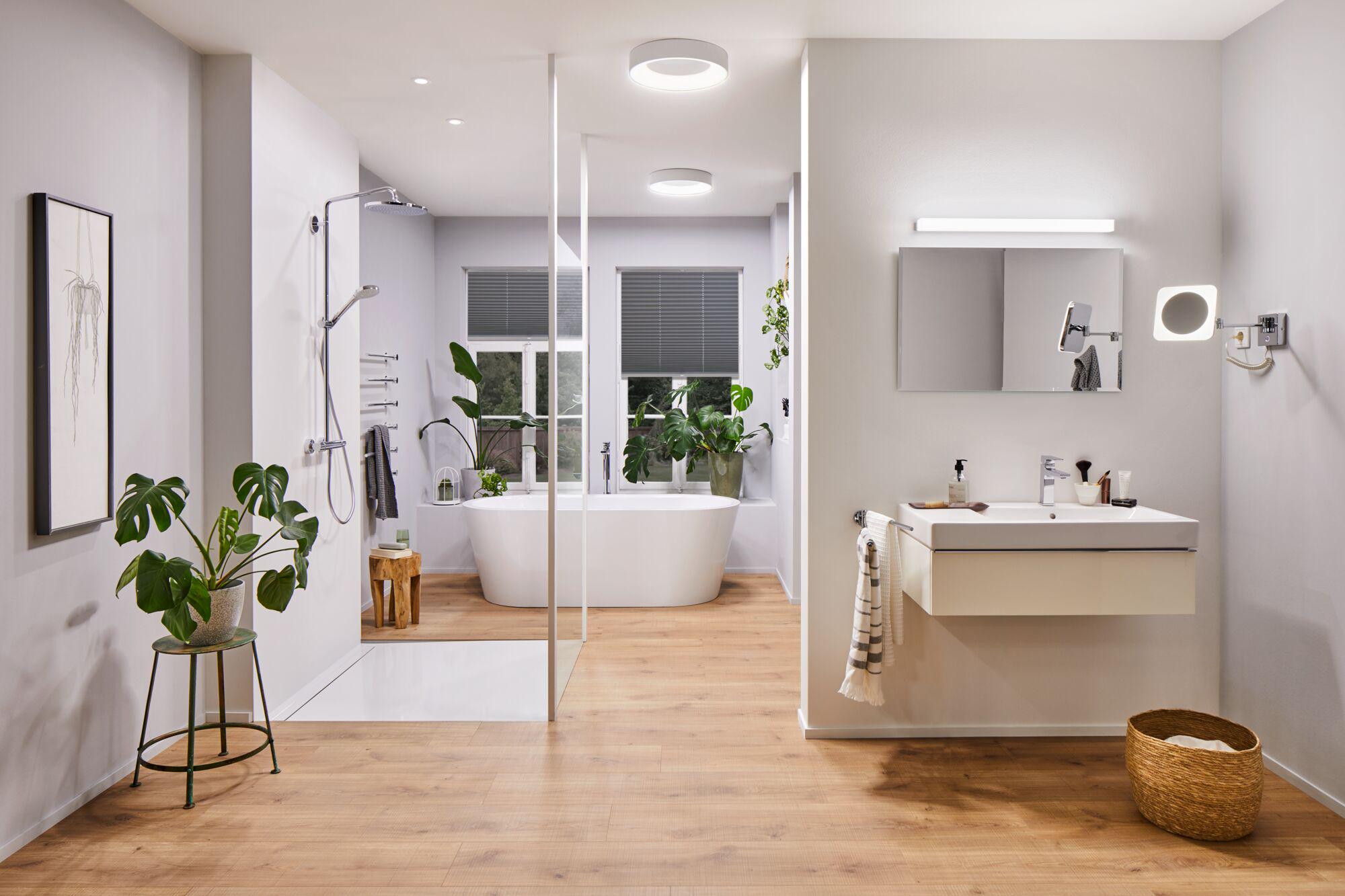 Modern bathroom with white bathtub, wooden floor and LED ceiling lights providing stylish room lighting
