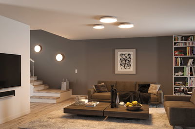 Moderne stue med brune sofaer, træbord og runde loftslamper med varmt hvidt lys.