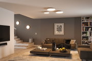 Modern living room with round white ceiling and wall lights, cozy furniture and bookshelf