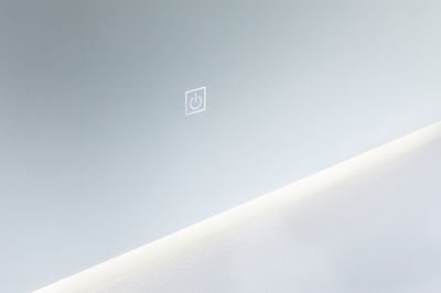 Modern wall mirror with integrated LED light and touch-sensitive power switch in white.