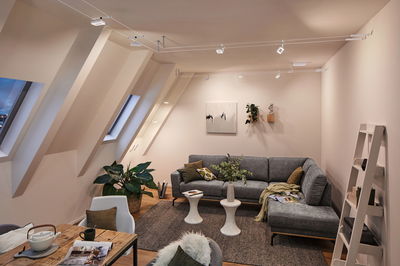 Moderne stue med grå stofsofa, hvide sideborde og Paulmann LED-kabelbelysning i loftet