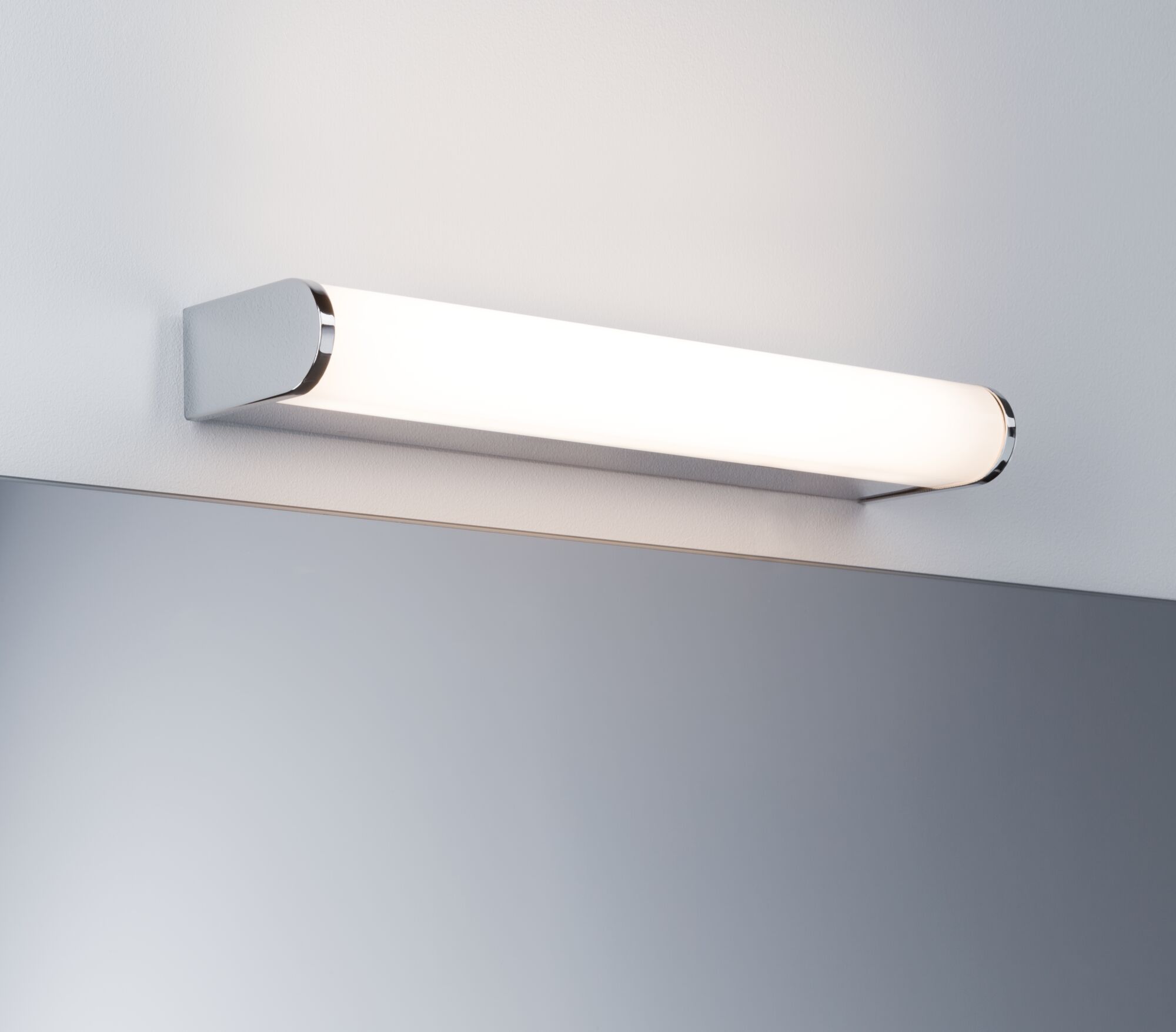 Modern white LED wall light with chrome end caps above a mirror for bathroom lighting